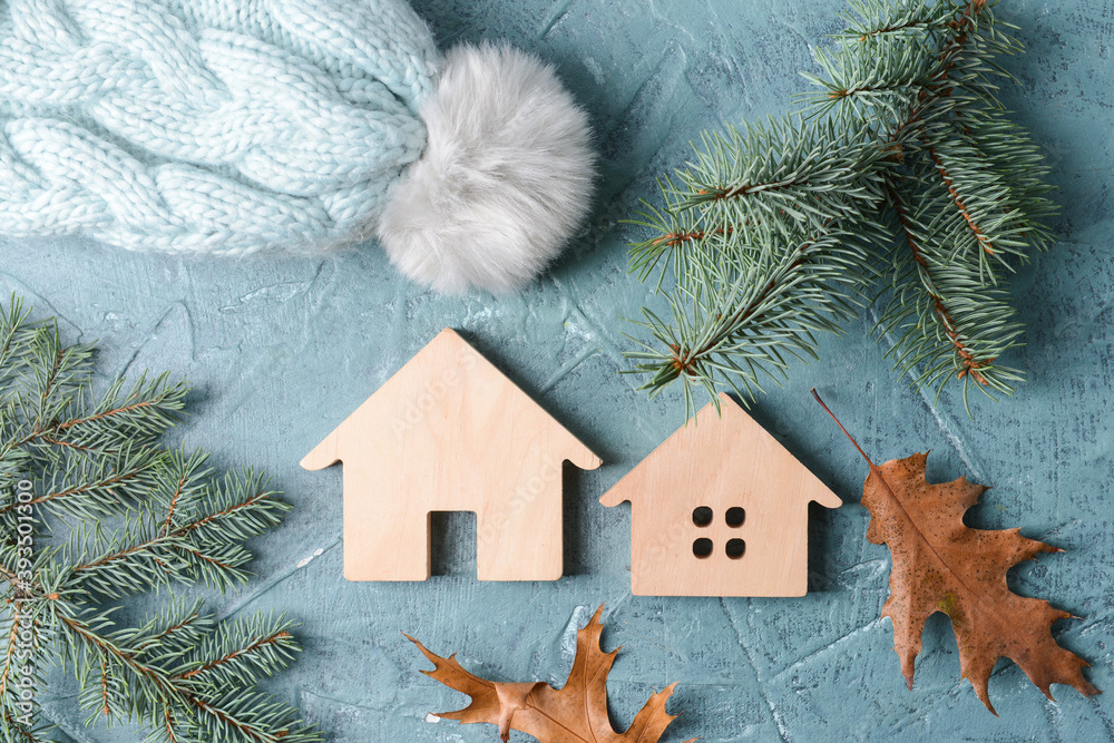 Figures of house, autumn leaves, fir branches and warm hat on table. Concept of heating season