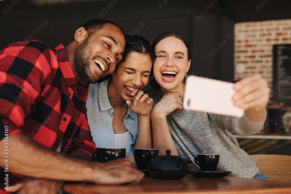 Friends in coffee shop having fun and taking selfies