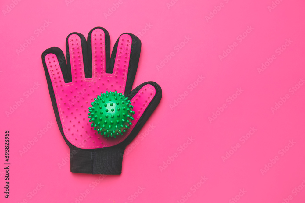 Pet grooming glove and ball on color background