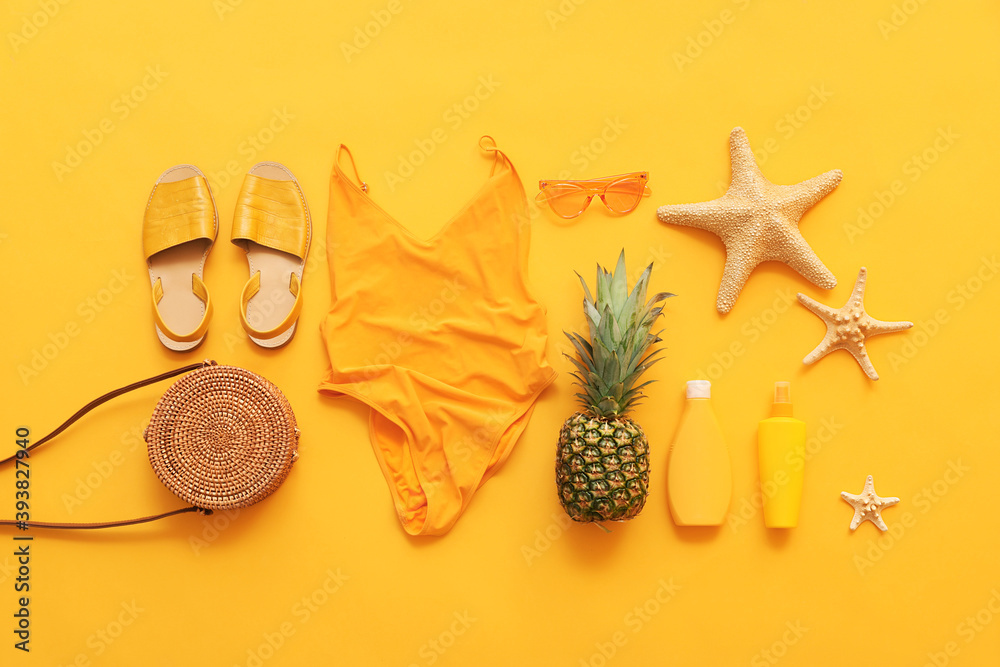 Set of beach accessories with female swimsuit on color background