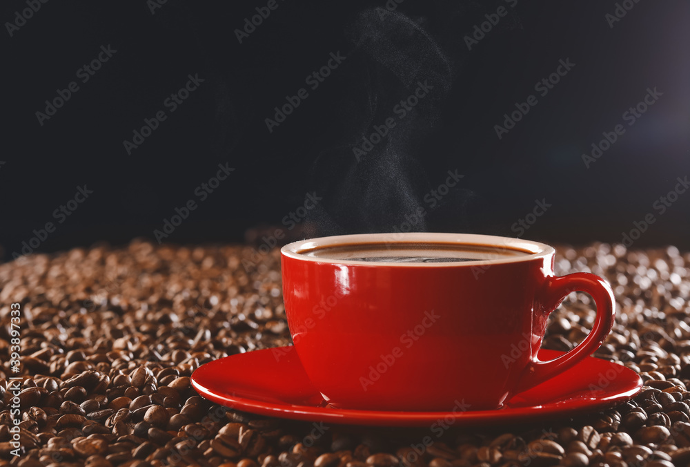 Cup of hot coffee and beans on dark background