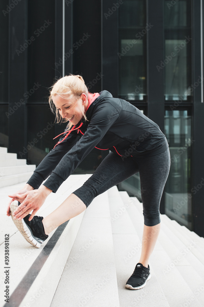 Junge, attraktive Frau dehnt sich auf einer Treppe