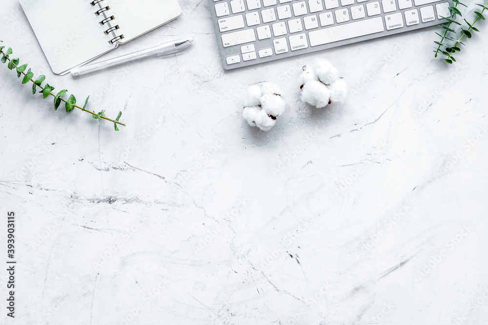 Laptop, cotton branch, notebook on white stone background flat lay copy space. freelancer, blogger h