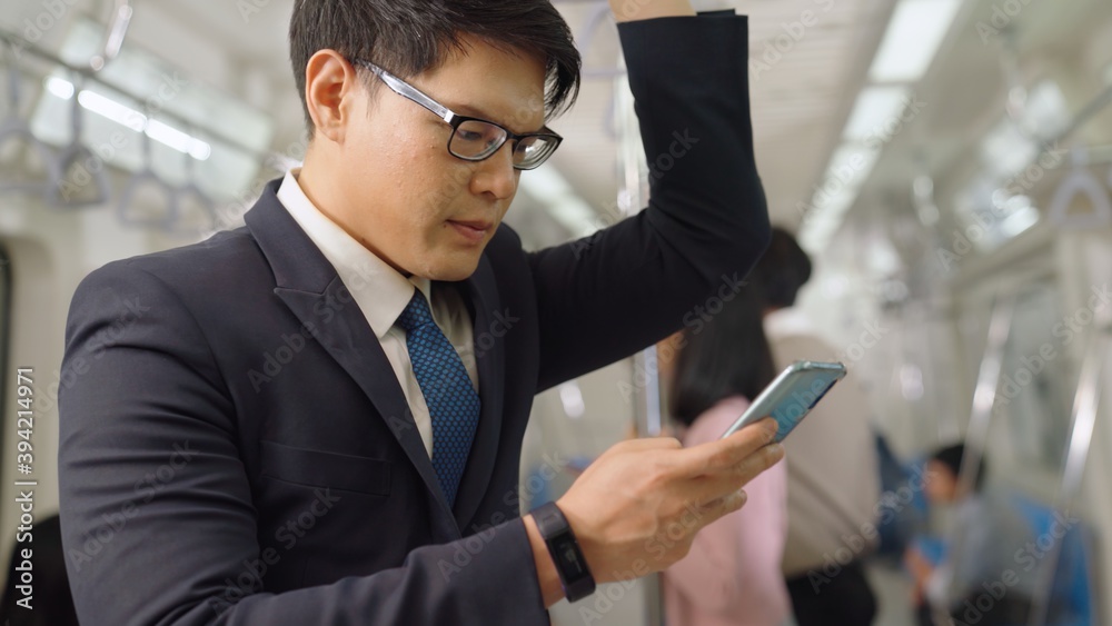 Businessman using mobile phone on public train . Urban city lifestyle commuting concept .