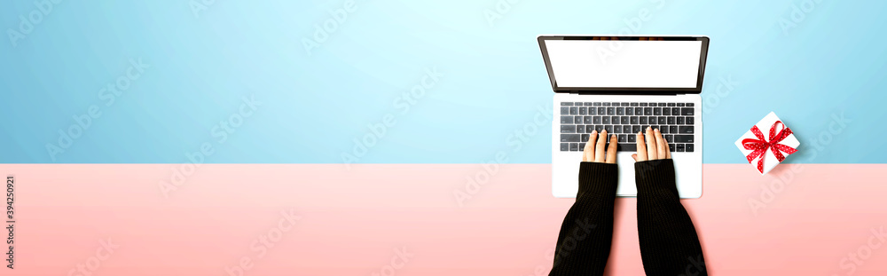 Person using a laptop computer with a gift box from above