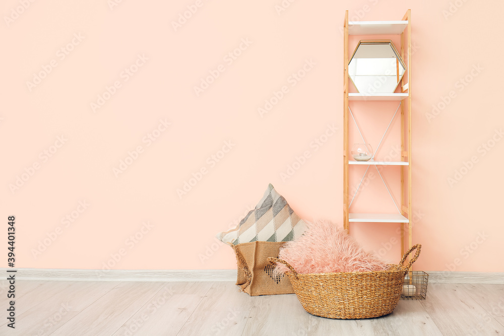 Wicker baskets with pillows and rack near color wall