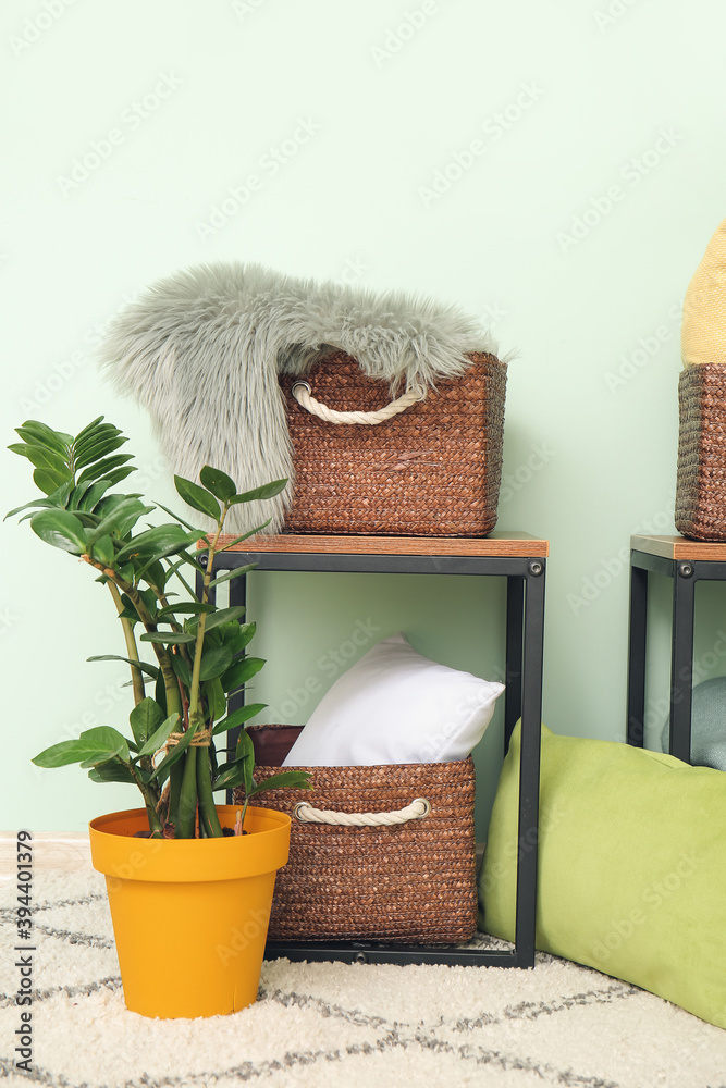 Wicker baskets with pillows, plaid and houseplant in room