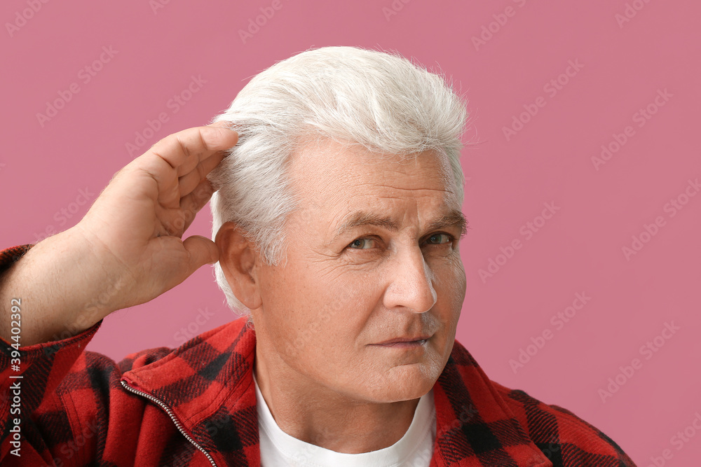 Stylish senior man with grey hair on color background