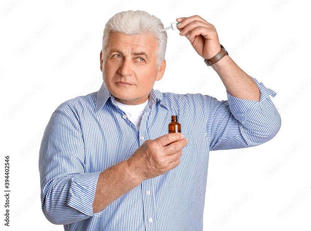 Senior man using serum for hair loss treatment on white background