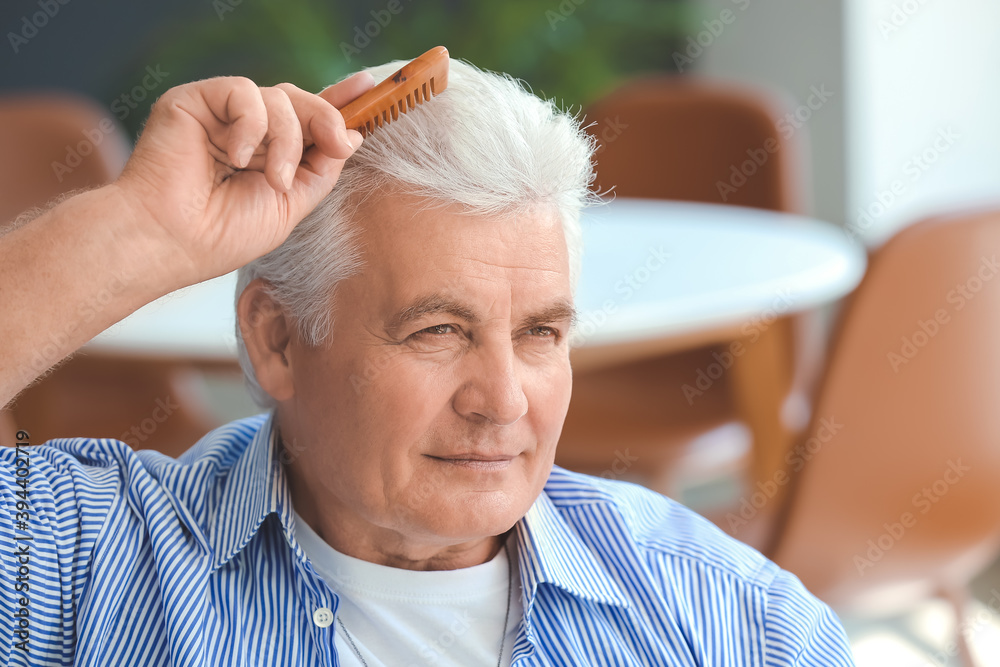 Senior man combing his hair at home