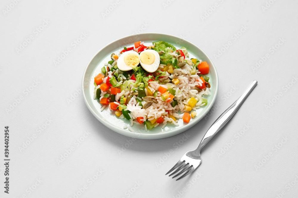 Plate of delicious rice salad with vegetables on light background