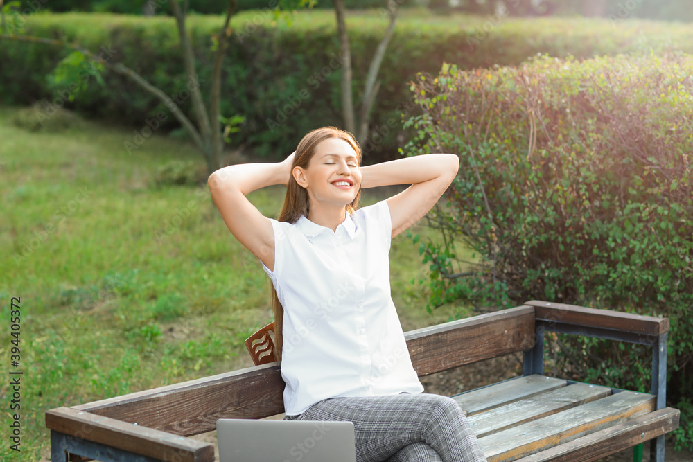 Beautiful young businesswoman relaxing in park