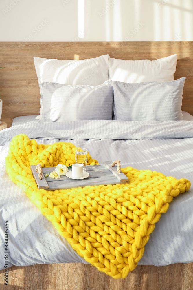 Knitted plaid with breakfast on bed at home