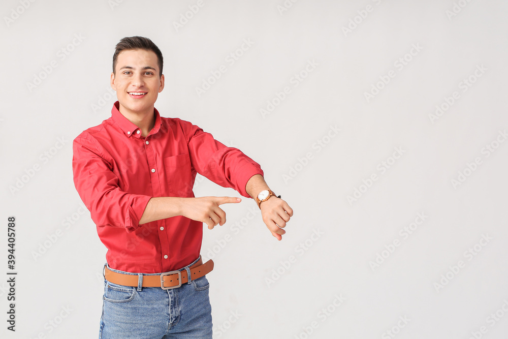 Young man with wristwatch on light background