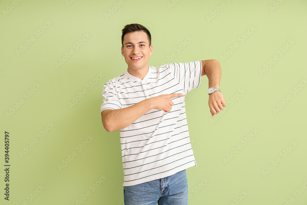 Young man with wristwatch on color background