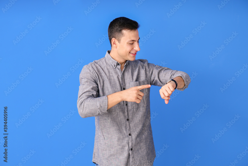 Young man with wristwatch on color background