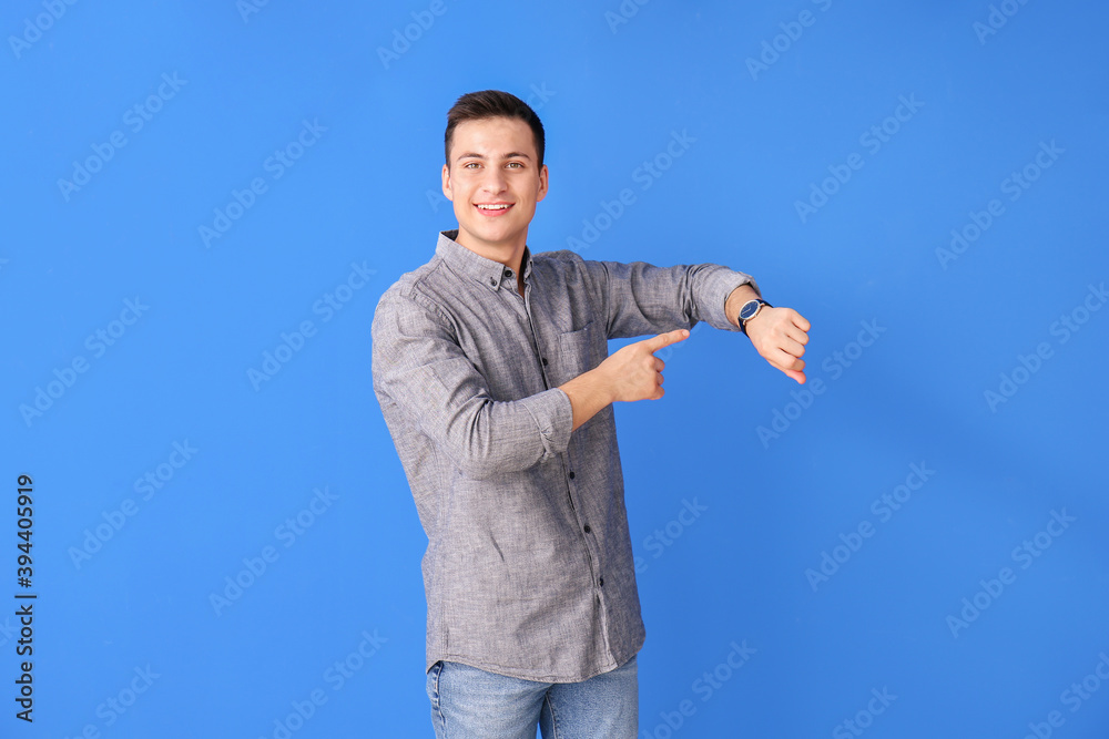 Young man with wristwatch on color background