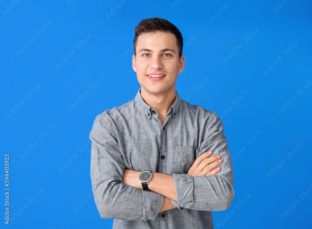 Young man with wristwatch on color background