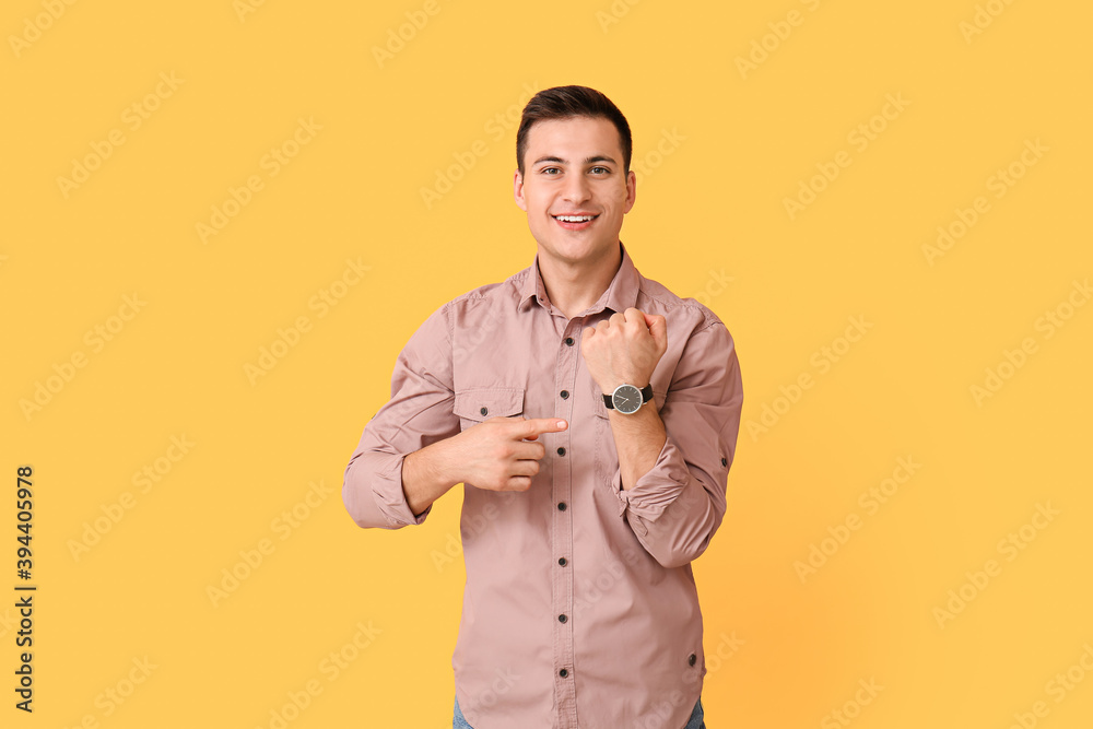 Young man with wristwatch on color background