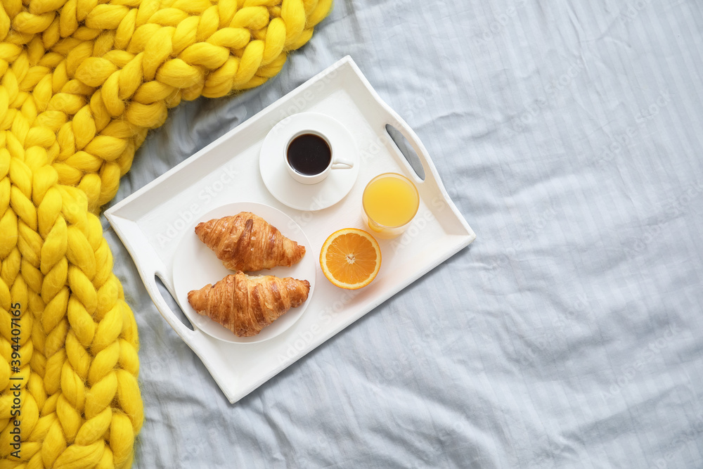 Tray with tasty breakfast on bed, top view