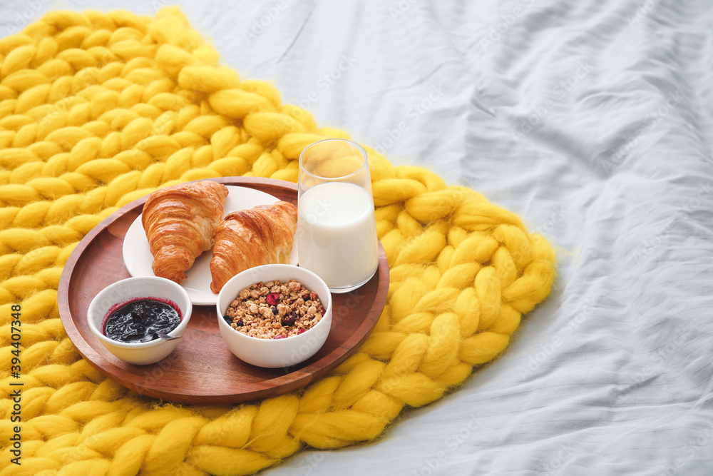 Tray with tasty breakfast on bed