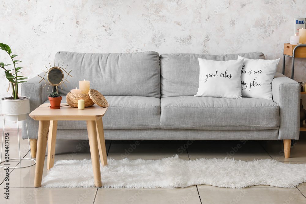 Stylish interior of living room with grey sofa and table with candles