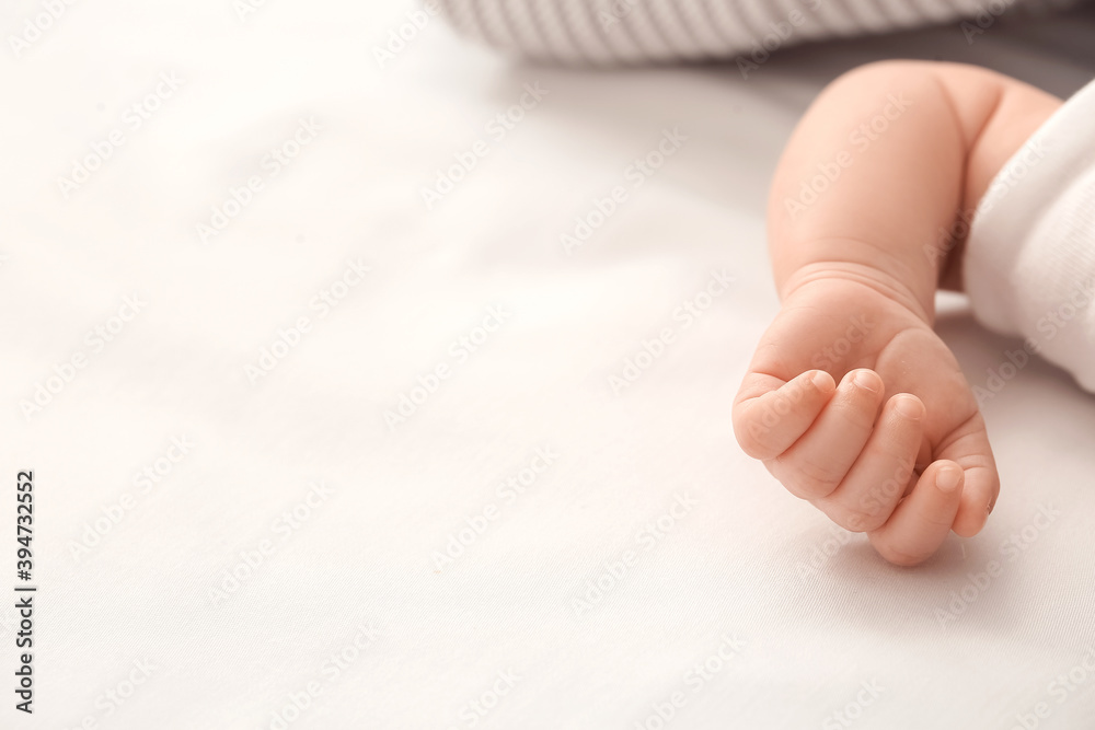 Hand of cute little baby lying on bed