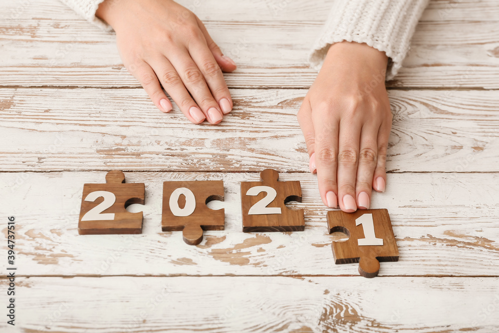 Woman and puzzle pieces with 2021 on table