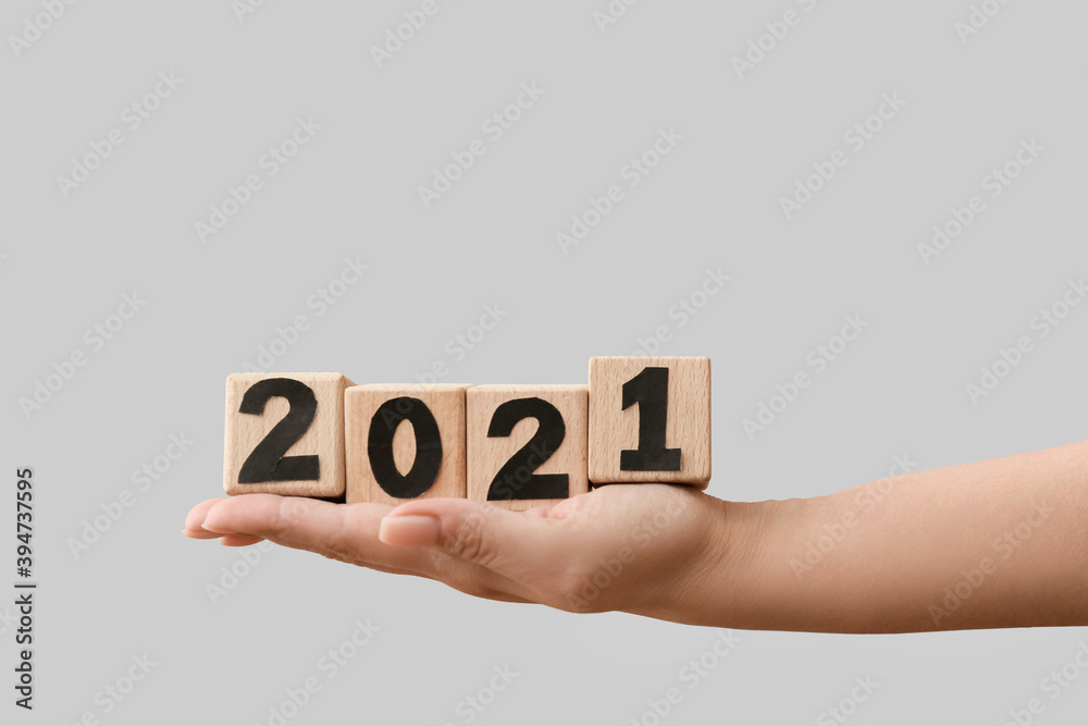 Female hand holding cubes with figure 2021 on light background