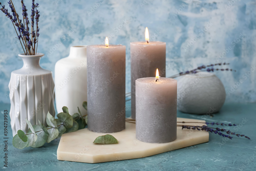 Beautiful aroma candles with lavender flowers on color background