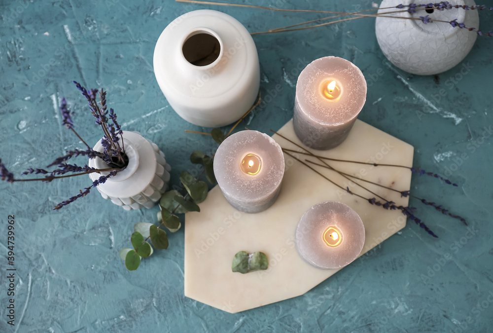 Beautiful aroma candles with lavender flowers on color background