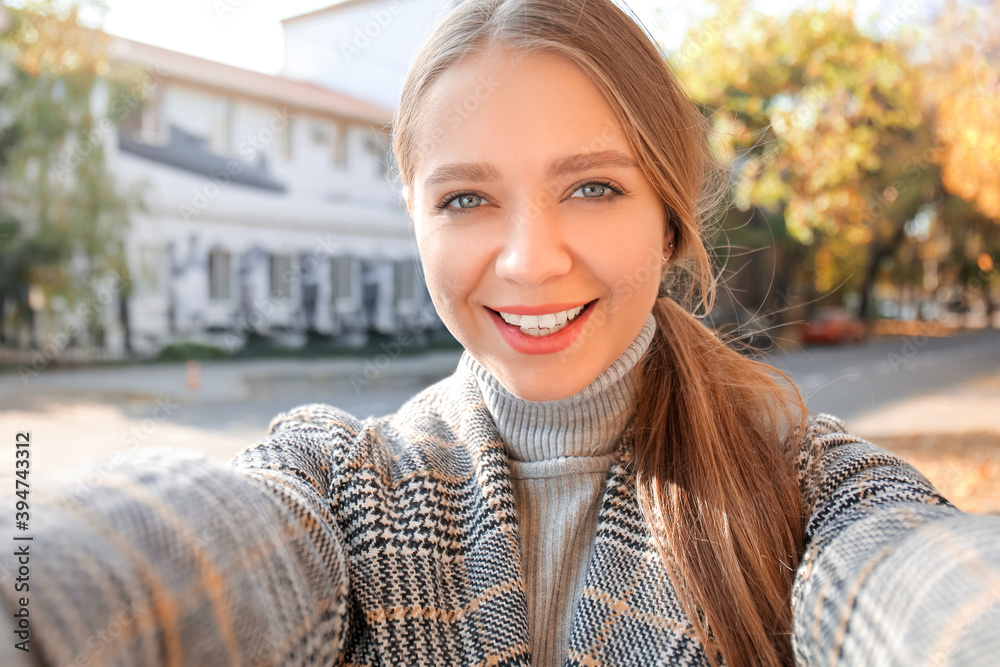 Beautiful young woman taking selfie outdoors