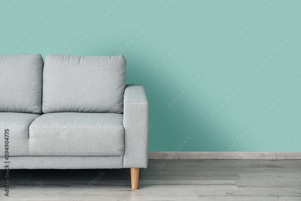 Stylish sofa near color wall in room