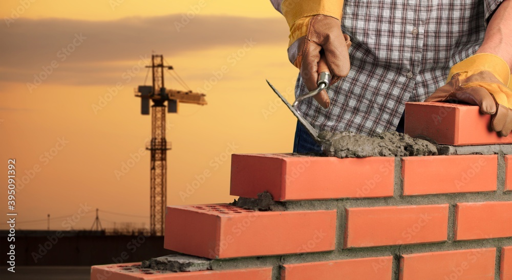 Man worker installing brick masonry wall with a trowel