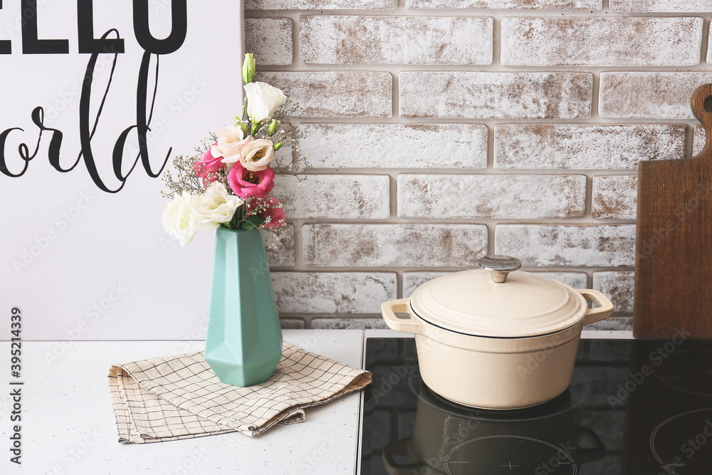 Stylish vase with bouquet of flowers in kitchen