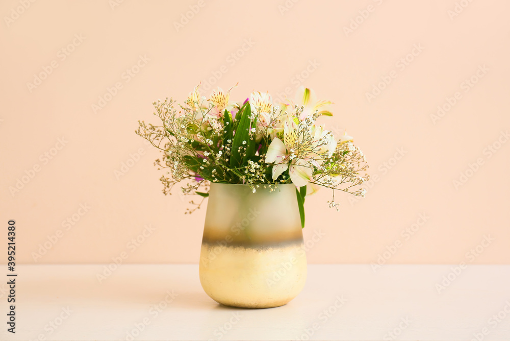 Beautiful vase with bouquet of flowers on light table against color background