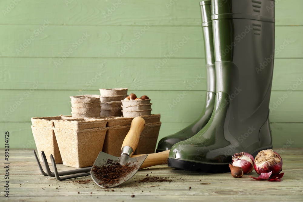 Gardening tools and gumboots on wooden background