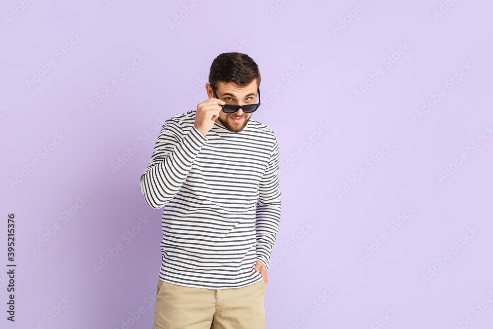 Handsome man with stylish sunglasses on color background