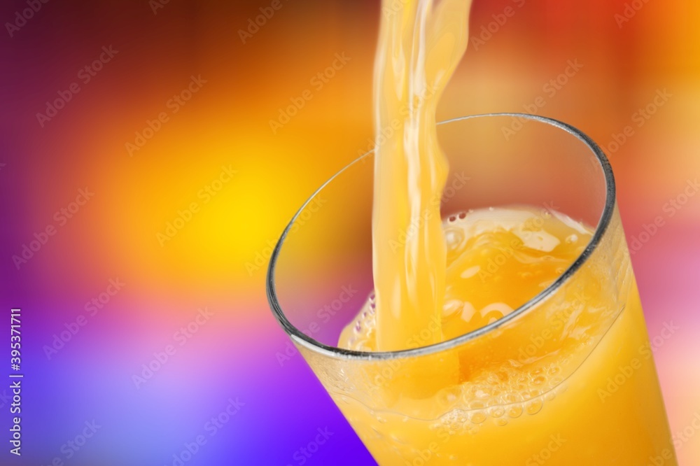 Orange juice pouring in glass on background