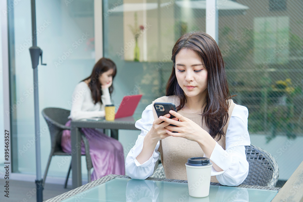 カフェテラスでスマホを使う女性