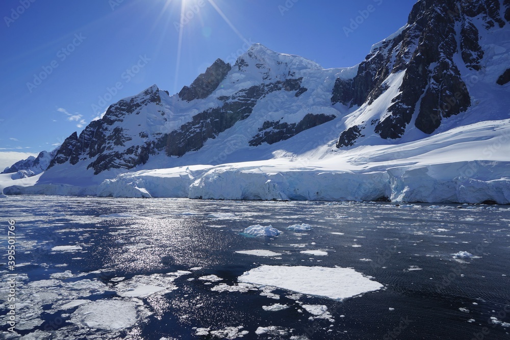 太阳悬在天空中，冰山融化的雪露出了岩石。南极的夏天