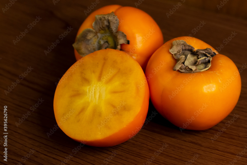 Fresh ripe persimmon fruits, cut on wooden background