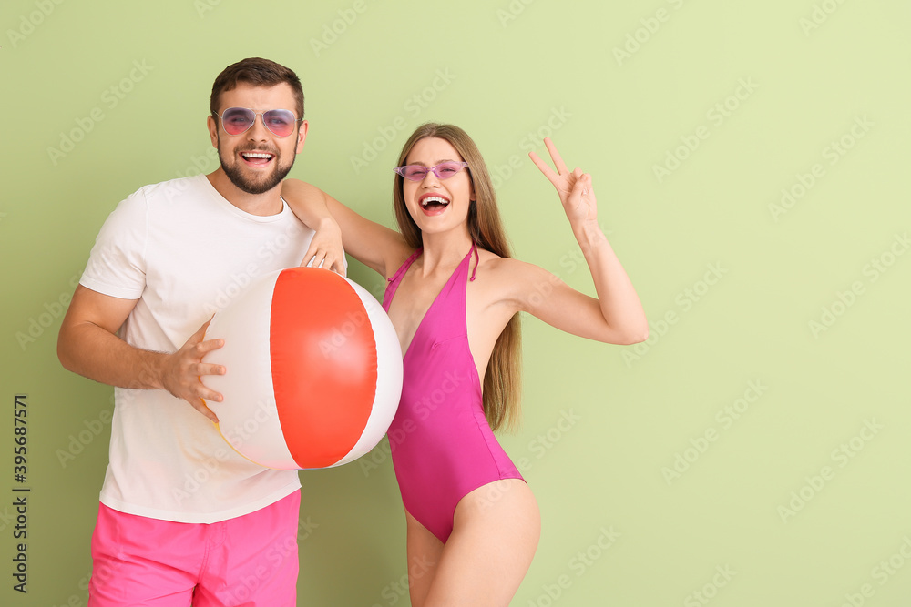 Young couple with stylish sunglasses and inflatable ball on color background