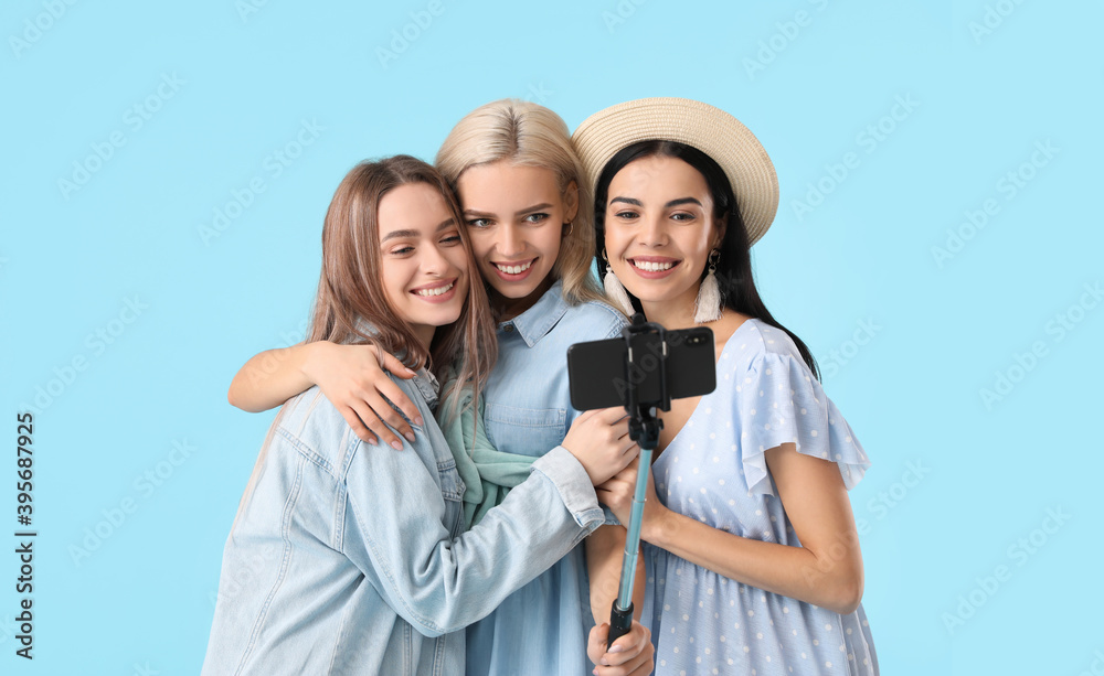 Beautiful young women taking selfie on color background