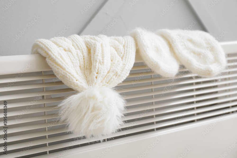 Warm hat and mittens on radiator. Concept of heating season