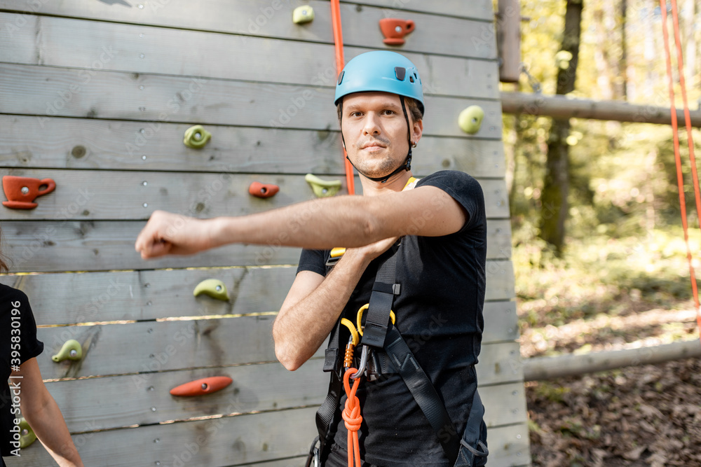 Young well-equipped sports couple warming up before climbing the wall in the park for sports enterta