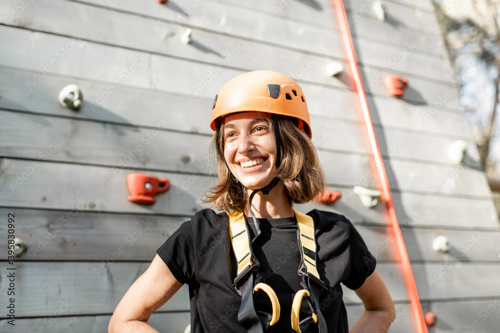 Portrait of a happy young woman in sports equipment near the climbing wall in the park for sports en