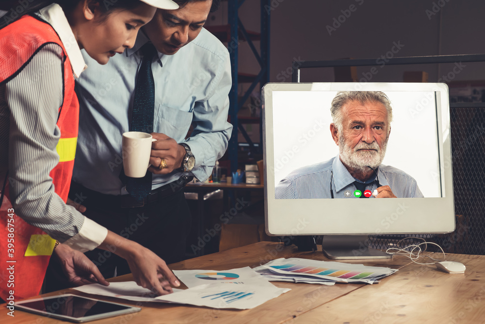 Warehouse staff talking on video call at computer screen in storage warehouse . Online software tech