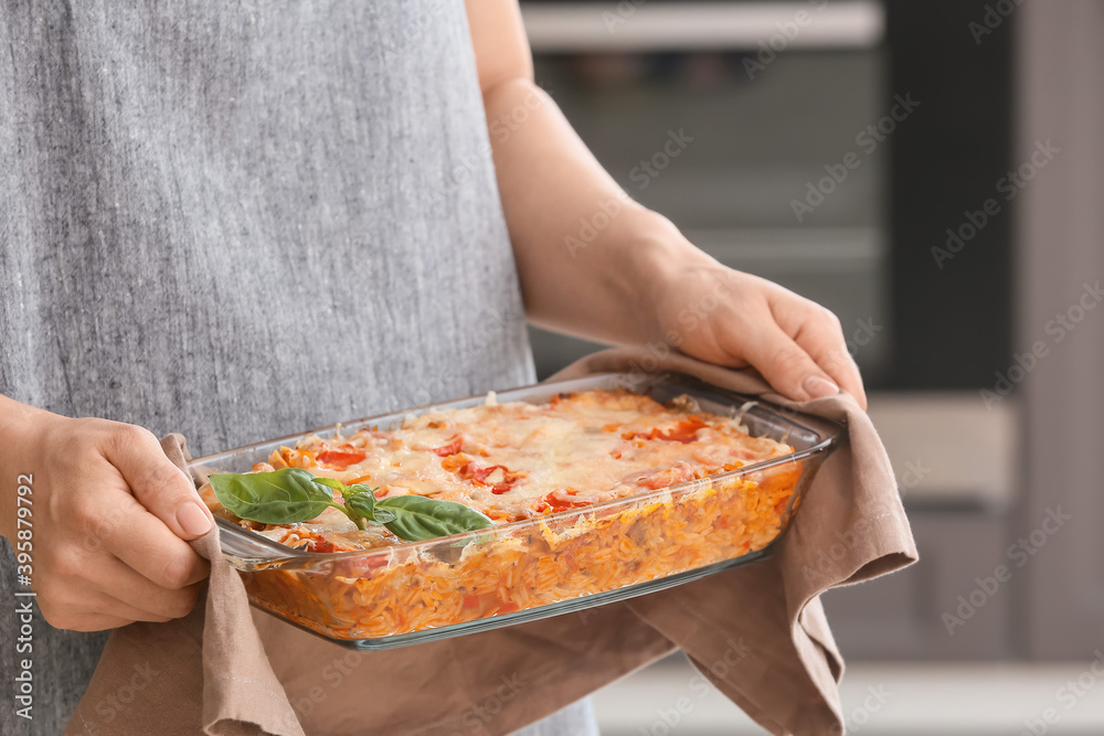 Woman with tasty rice casserole in kitchen, closeup