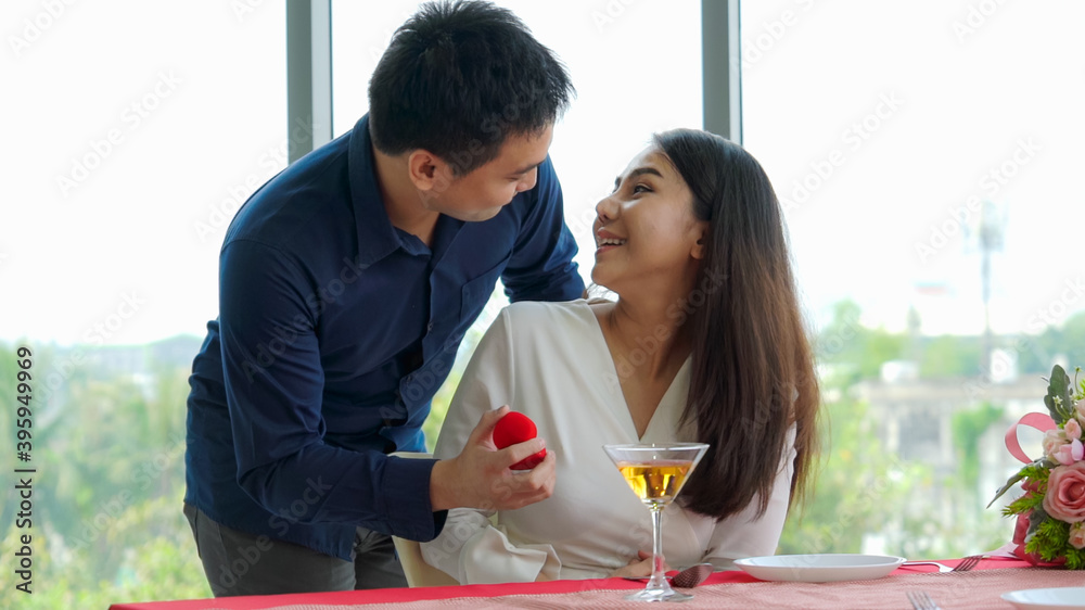 Romantic couple giving gift to lover at restaurant . Happy couple lifestyle .